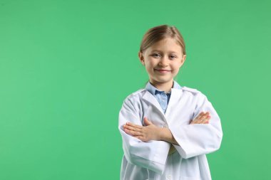 Yeşil arka planda laboratuvar önlüklü şirin küçük kız, mesaj için yer var. Çocuk ve bilim