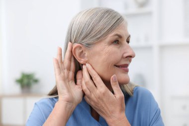 Evde işitme cihazı olan yaşlı bir kadın var.