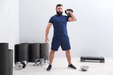 Spor salonunda kettlebell ile egzersiz yapan güçlü bir adam.