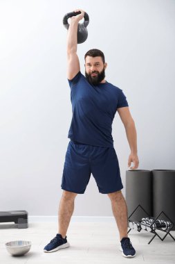 Spor salonunda kettlebell ile egzersiz yapan güçlü bir adam.