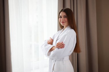 Otel odasının penceresinin yanında beyaz bornoz giyen güzel bir kadın. Metin için boşluk