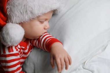 Noel pijamalı bebek ve Noel Baba şapkalı, yatakta uyuyor. Metin için boşluk