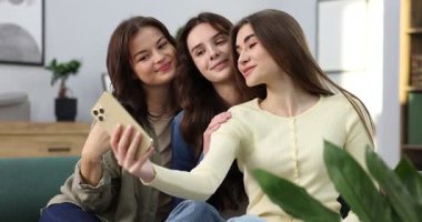 Üç arkadaş evdeki kanepede selfie çekiyorlar.