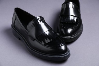 Gri arka planda şık siyah ayakkabılar, yakın plan.