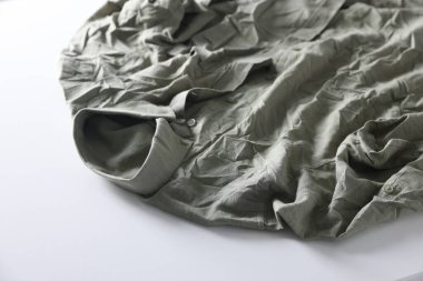 Açık arkaplanda yeşil buruşuk gömlek, yakın plan.