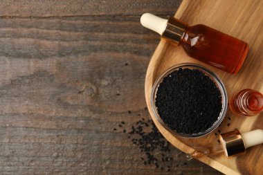 Kasede siyah kimyon tohumları, pipet ve ahşap masa üzerinde gerekli yağ şişeleri, üst manzara. Metin için boşluk