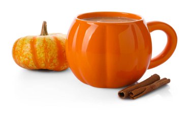 Bardakta sıcak kabaklı latte, tarçınlı çubuklar ve beyaz üzerine taze sebze.