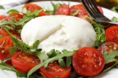 Lezzetli burrata peyniri roka ve tabakta domates, yakın plan.