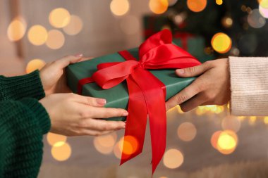 Mutlu Noeller ve mutlu yıllar. Kapalı mekandaki arkadaşına hediye kutusu veren bir kadın.