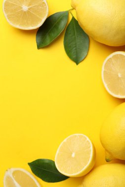 Taze olgun limonlar ve sarı arka planda yapraklar, düz. Metin için boşluk