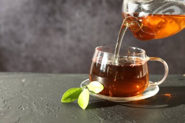Siyah masada çaydanlıktan fincana sıcak çay dökmek, yakın plan. Metin için boşluk
