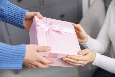 Mutlu Noeller ve mutlu yıllar. Kapalı mekandaki arkadaşına hediye kutusu veren bir kadın.