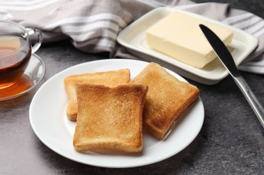 Taze kızarmış ekmek dilimleri, tereyağı ve çay ile servis edilir, yakın plan.