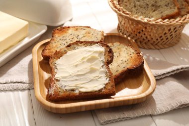 Beyaz ahşap masada tereyağlı ekmek dilimleri, yakın plan.