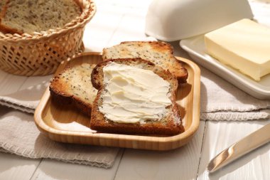 Beyaz ahşap masada tereyağlı ekmek dilimleri, yakın plan.