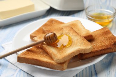 Hafif ahşap masada ballı taze kızarmış ekmek, yakın plan.