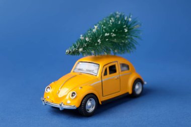 Noel tatili. Mavi arka planda ağaç olan oyuncak araba