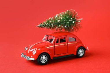 Noel tatili. Kırmızı arka planda ağaç olan oyuncak araba
