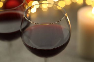 Bulanık ışıklara karşı kırmızı şarap kadehleri, yakın plan. Noel ve Yeni Yıl Kutlaması