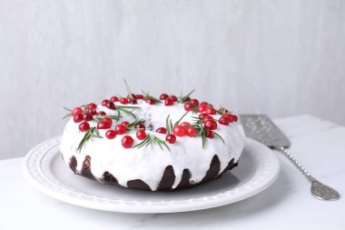 Beyaz masada yaban mersinli ve biberiyeli lezzetli bir Noel pastası.