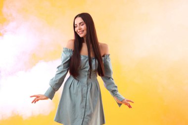 Turuncu arka planda poz veren güzel giyimli kadın dumanlı, mesaj için yer var.