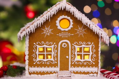 Masanın üzerinde bulanık ışıklara karşı güzel zencefilli kurabiye evi, yakın plan. Noel hediyesi