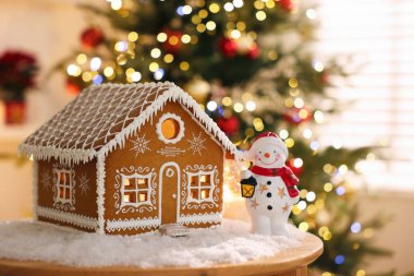 Güzel zencefilli kurabiye evi, kardan adam figürü ve masa üzerindeki yapay kar kapalı alanda bulanık ışıklara karşı, metin için yer ile yakın çekim. Noel atmosferi