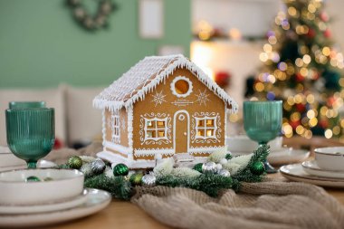 Kapalı mekandaki bulanık ışıklara karşı güzel zencefilli kurabiye eviyle şenlik masası. Noel atmosferi