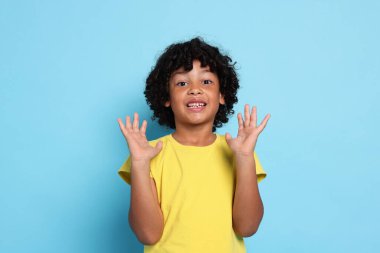 Açık mavi arka planda şaşırmış küçük bir çocuğun portresi