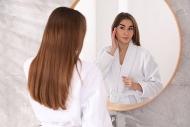 İçerideki aynanın yanında bornozlu güzel bir kadın.