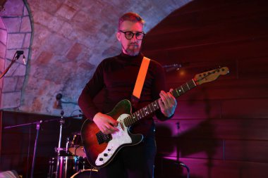 Sahnede gitar çalan yakışıklı adam.