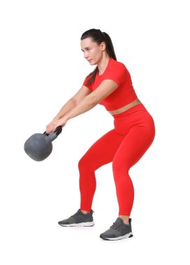 Beyaz arka planda kettlebell egzersizi yapan atletik kadın.