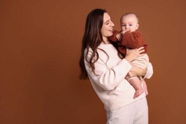 Kahverengi arka planda sevimli bebeğiyle mutlu bir anne. Metin için boşluk