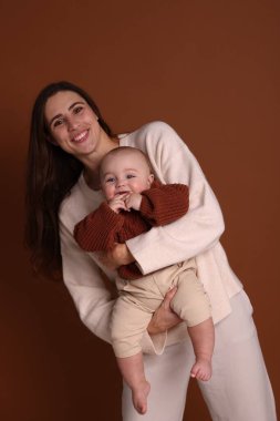 Kahverengi arka planda sevimli bebeğiyle mutlu bir anne.
