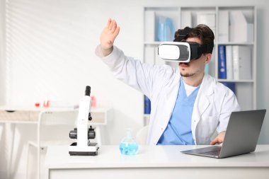 Modern teknoloji. Ofiste masasında sanal ekran kullanan kulaklıklı bir doktor. Metin için boşluk