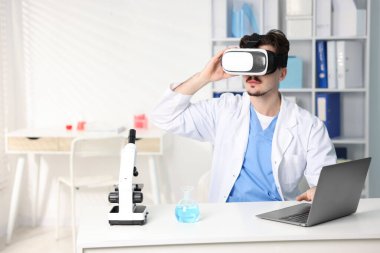 Modern teknoloji. Ofisteki masada sanal gerçeklik kulaklığı kullanan bir doktor. Metin için boşluk