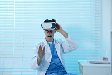Modern teknoloji. Ofisteki masada sanal gerçeklik kulaklığı kullanan bir doktor. Metin için boşluk