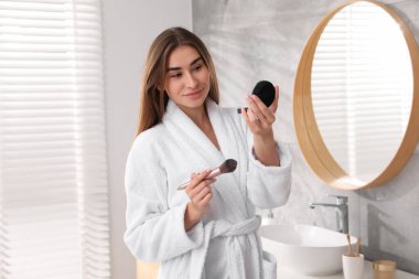 Bornozlu, yüz pudralı ve kapalı mekanlı güzel bir kadın.