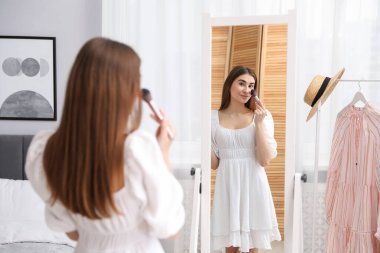 Güzel bir kadın aynanın yanında makyaj yapıyor.