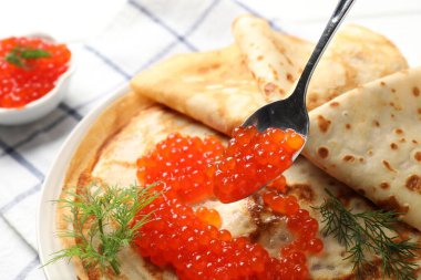 Masadaki ince kreplere kırmızı havyar ekliyorum, yakın plan.