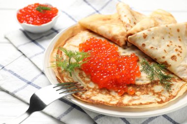 Beyaz ahşap masada servis edilen kırmızı havyarlı leziz krepler.