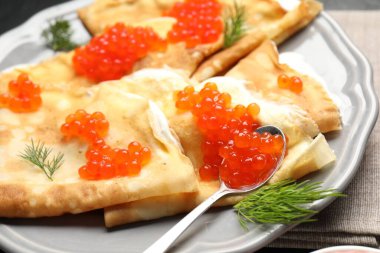 Kırmızı havyarlı leziz krepler, ekşi krema ve dereotu masada, yakın plan.