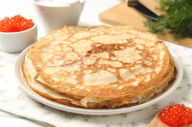 Kırmızı havyarlı lezzetli krepler, ekşi krema ve dereotlu masa, yakın plan.