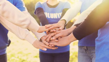 Güneşli bir günde dışarıda el ele tutuşan bir grup gönüllü, kapatıyoruz. Pankart tasarımı