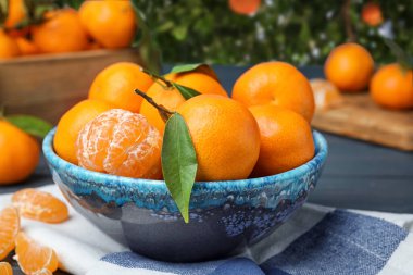 Ağacın yanındaki masada taze, sulu mandalinalar var.