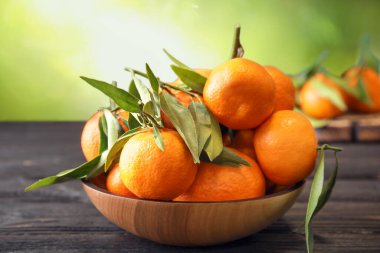 Tahta masada, yeşil arka planda taze, sulu mandalinalar.