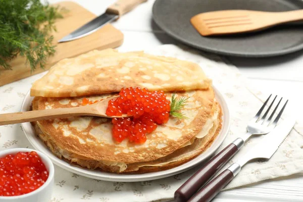 Kırmızı havyarlı leziz krepler ve beyaz ahşap masadaki dereotlar, yakın plan.