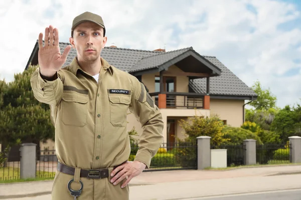 Özel mülk koruması için güvenlik görevlisi. Üniformalı adam evin önünü kapatıyor.