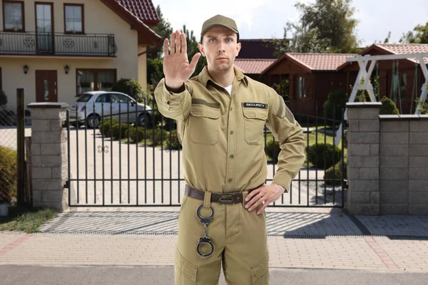 Dışarıdaki evin önünü kapatan üniformalı bir güvenlik görevlisi. Özel mülk koruması