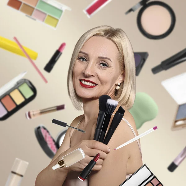 Bej arka planda fırçaları olan güzel bir kadın. Farklı dekoratif kozmetik ürünleri makyaj sanatçılarının etrafında düşüyor.